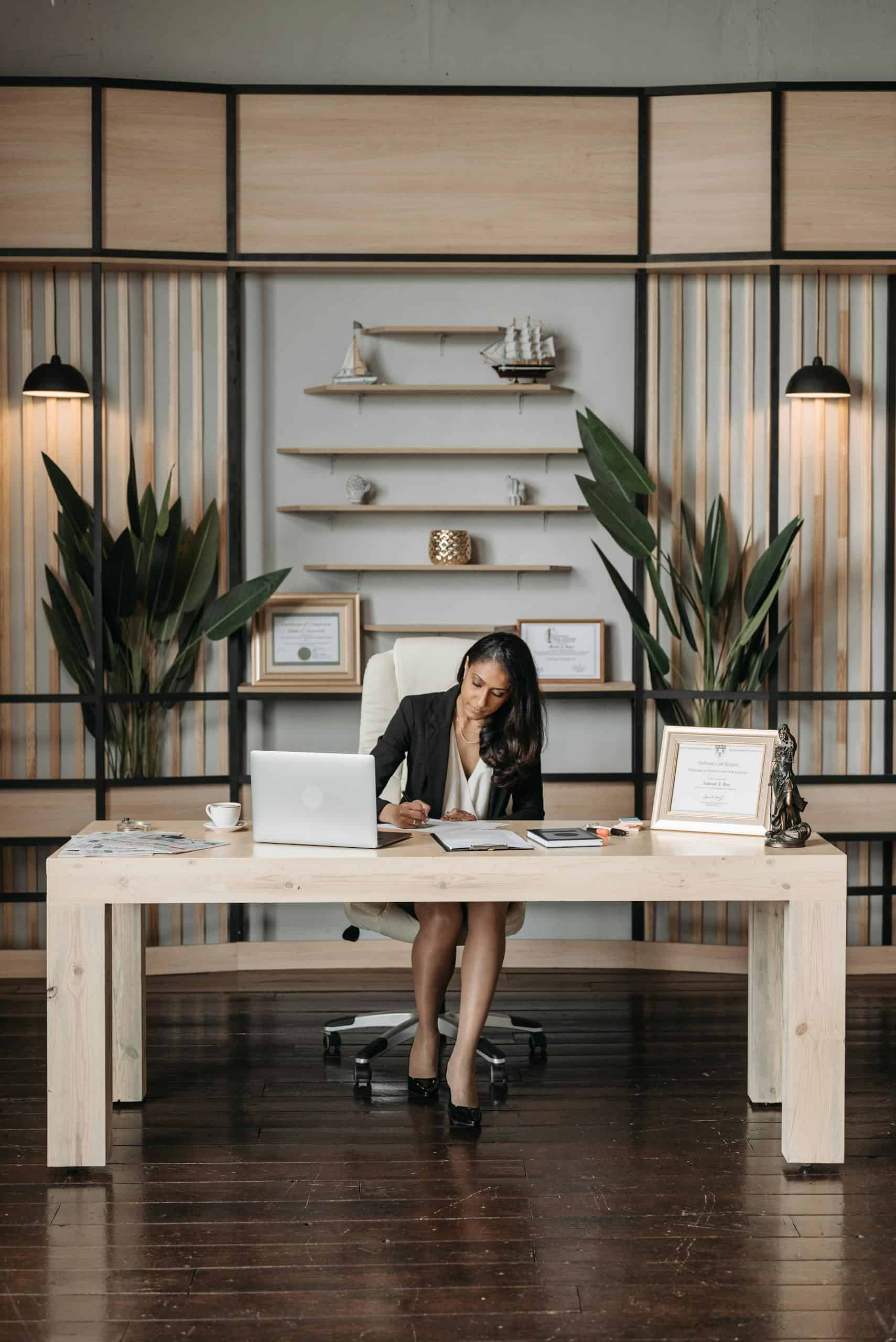 Professional woman in office writing at desk, working on self assessment and tax returns.